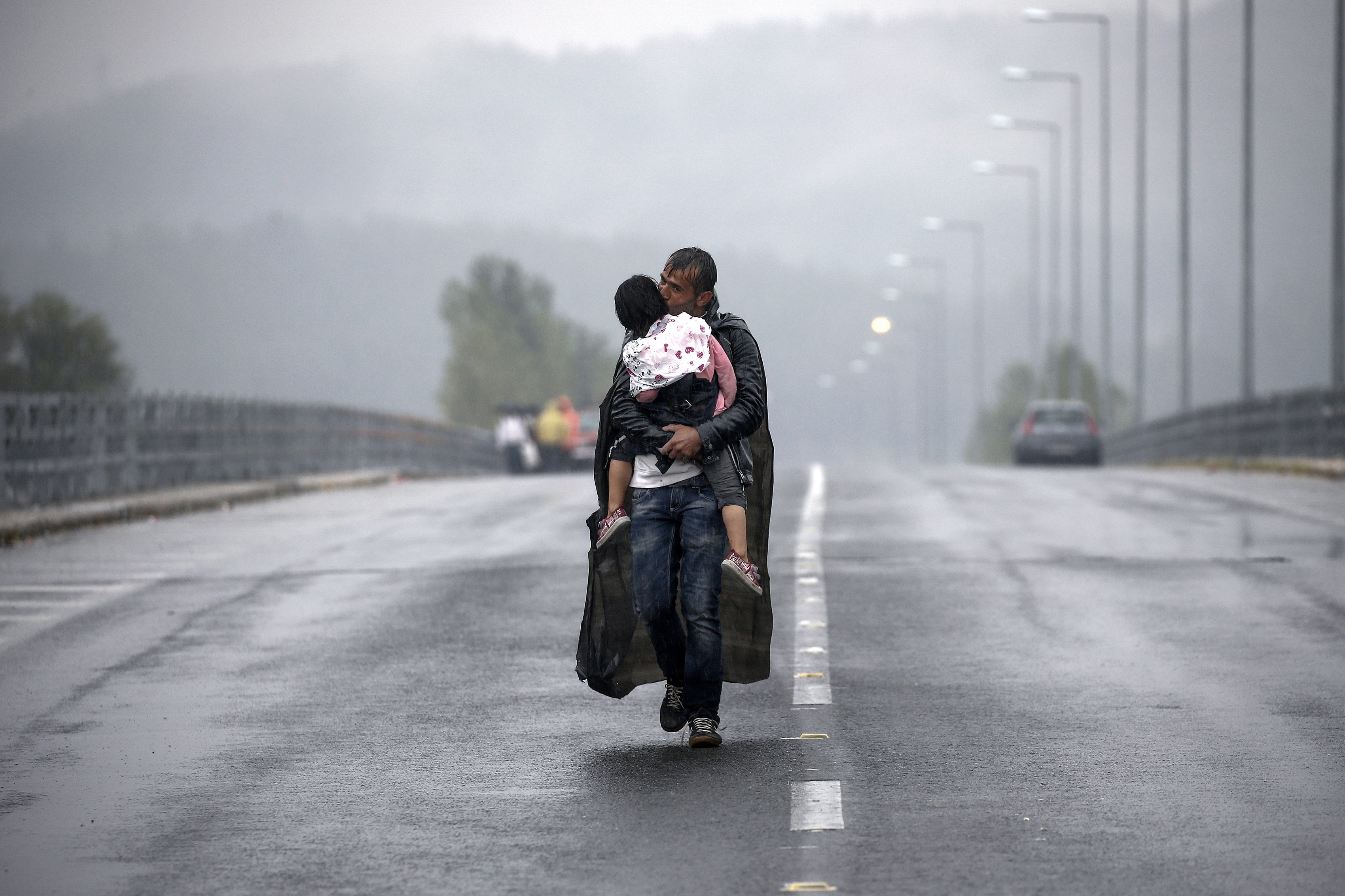 A Syrian refugee kisses his daughter as he walked for hours through a rainstorm to reach Greece's border with FYRO-Macedonia, near the Greek village of Idomeni, September 10, 2015. Thousands of refugees and migrants, including many families with young children, have been left soaked after spending the night sleeping in the open in torrential rain on the Greek- FYRO Macedonian border. About 7,000 people waited in the mud at an open field near the northern Greek village of Idomeni to cross the border, with more arriving in trains, buses and taxis, as FYRO Macedonian police has imposed rationing in the flow of refugees.